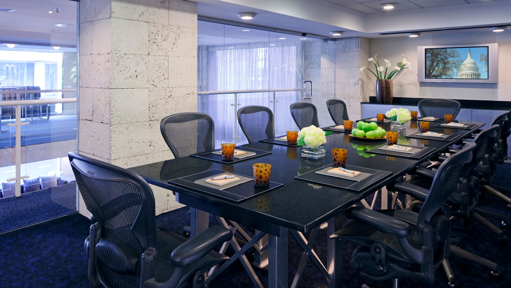 Boardroom set up for a meeting with notepads, pens, and water at Kimpton Hotel George