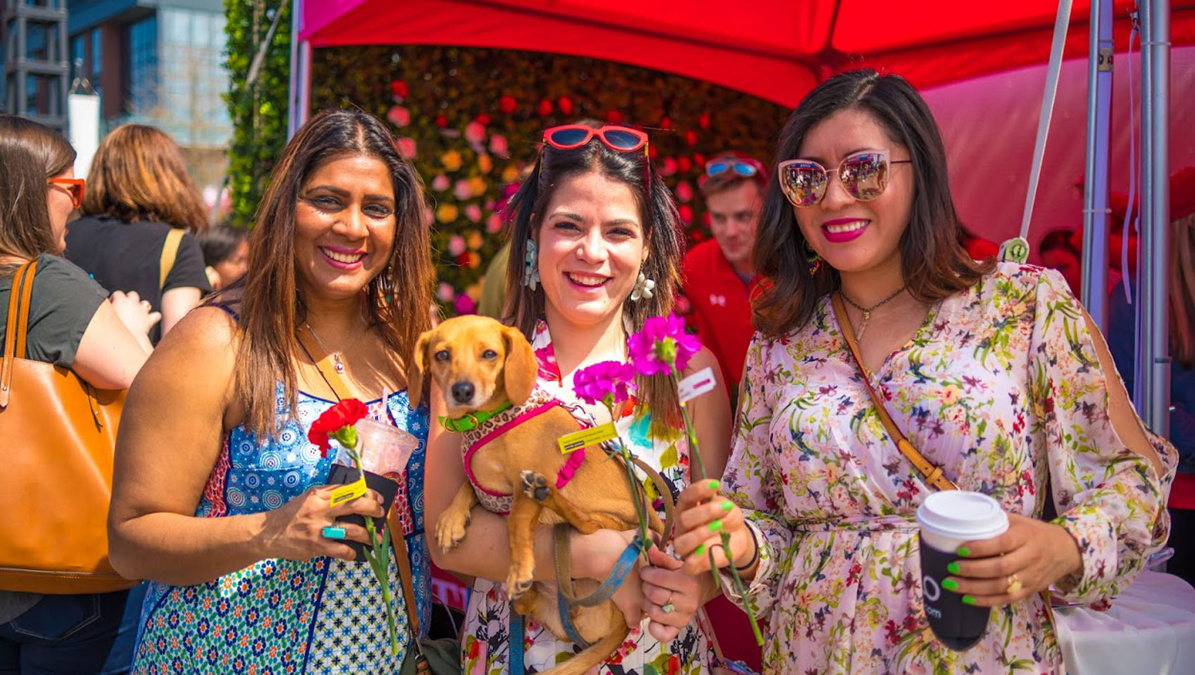 3 women pose together with a dog, all smiling at the Cherry Blossom Festival